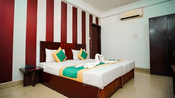 Une chambre d’hôtel avec un grand lit, une tête de lit en bois et un mur à rayures rouges et blanches.