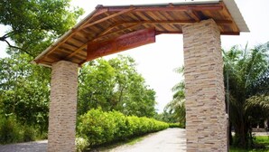 A stone archway with a wooden roof and a sign that reads "Paradise." - Hotel Magic Paradise (Nueva Loja)