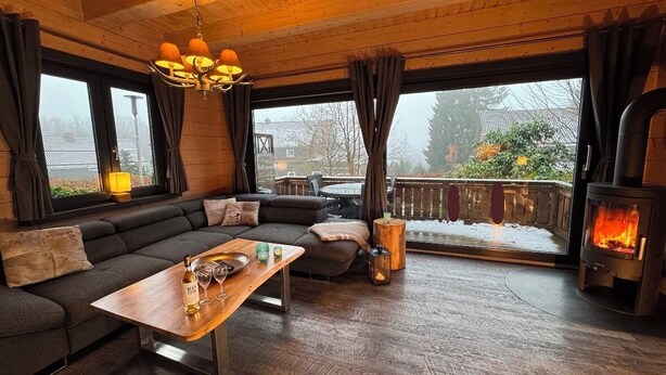 Un salon chaleureux avec un plafond en bois, une grande fenêtre, un canapé, une table basse et une cheminée.