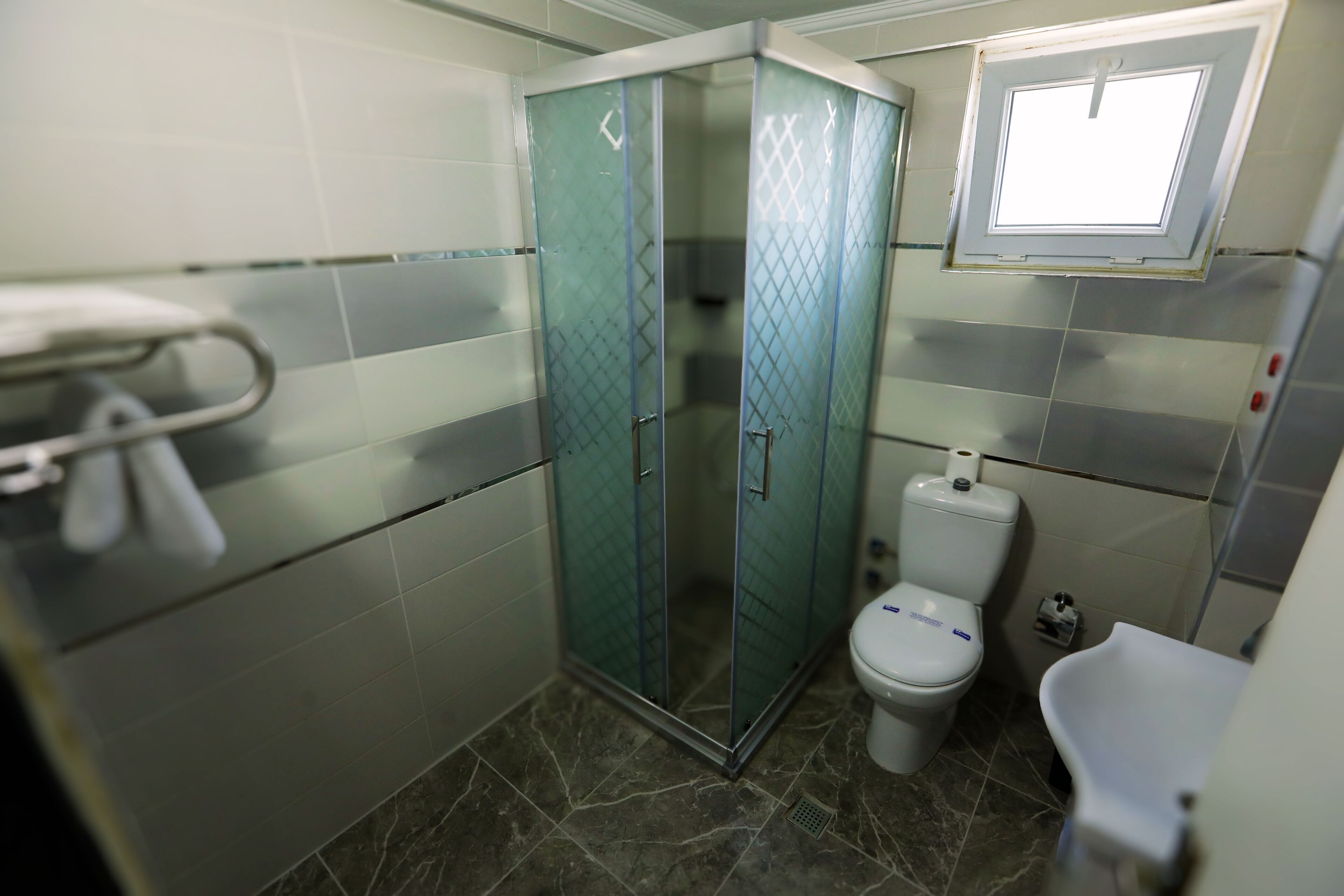 A bathroom with a glass-enclosed shower, a toilet, and a sink.