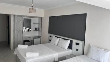 Habitación de hotel con dos camas, un escritorio, un espejo y un refrigerador pequeño.