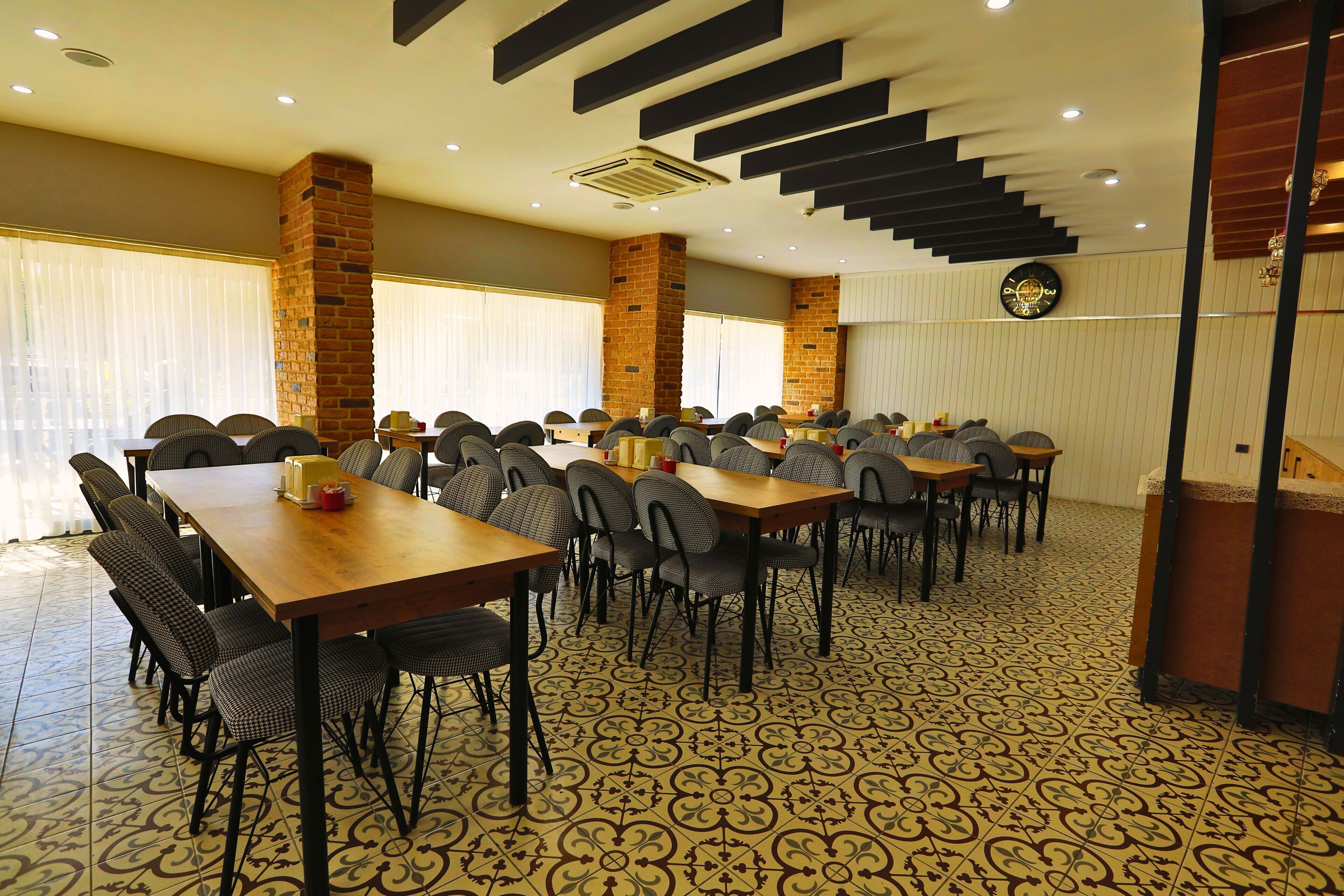 A conference room with multiple tables and chairs, a brick pillar, and a patterned floor.