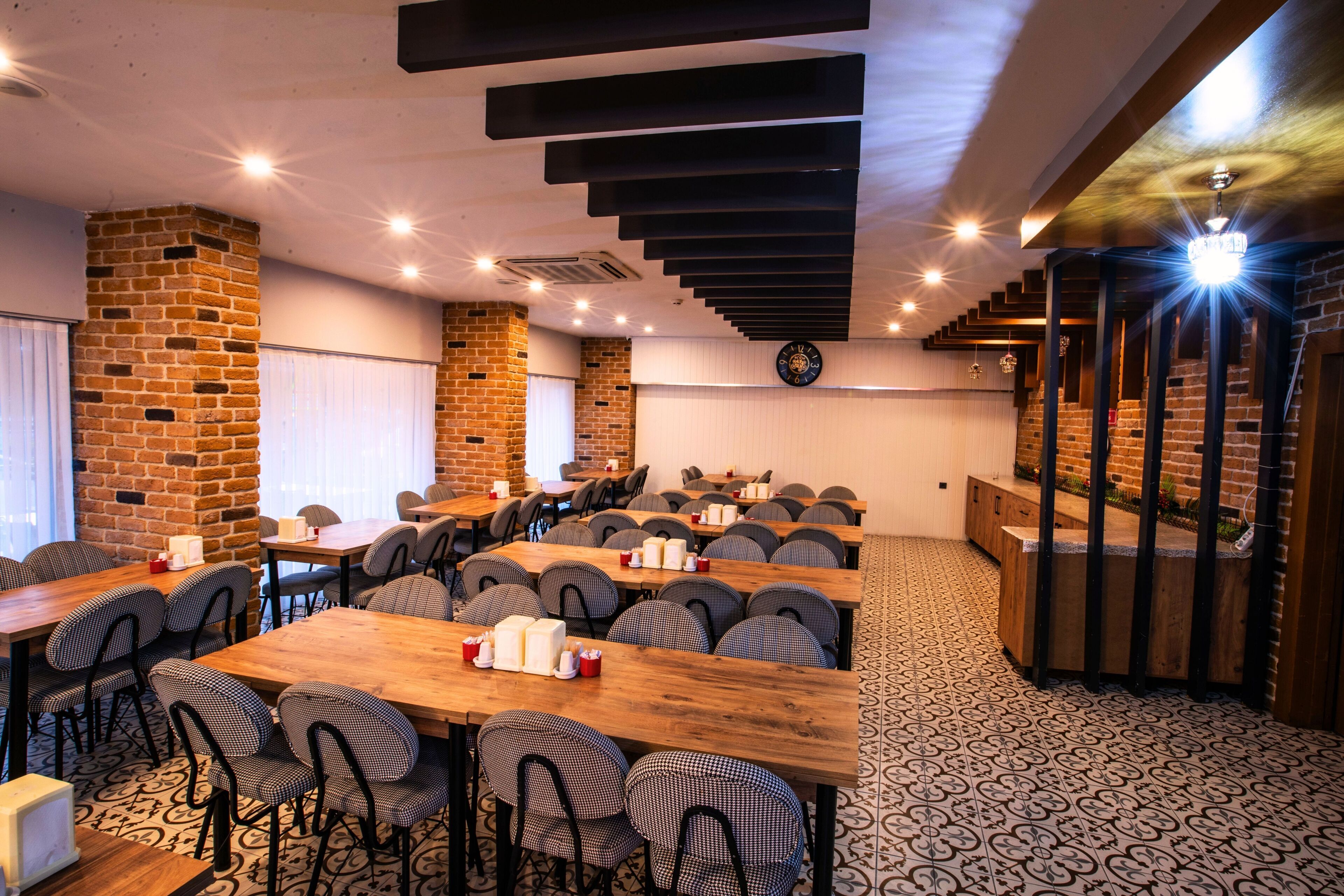 A conference room with long tables and chairs, a brick wall, and a staircase.