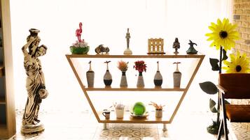 A room with a decorative shelf holding various items, a statue, and a sunflower.