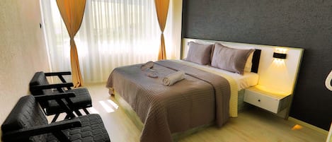 Una habitación de hotel con cama, mesita de noche, escritorio y silla.