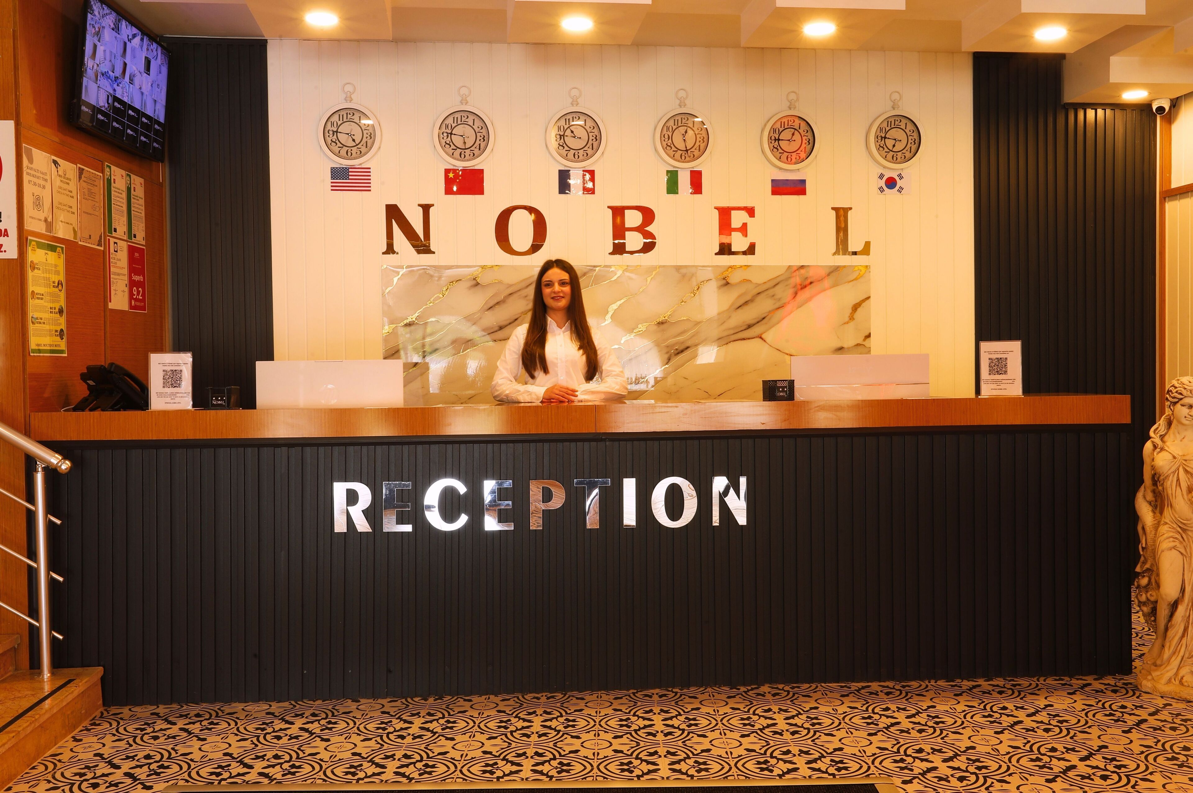A reception desk with a marble wall behind it displaying clocks and flags.