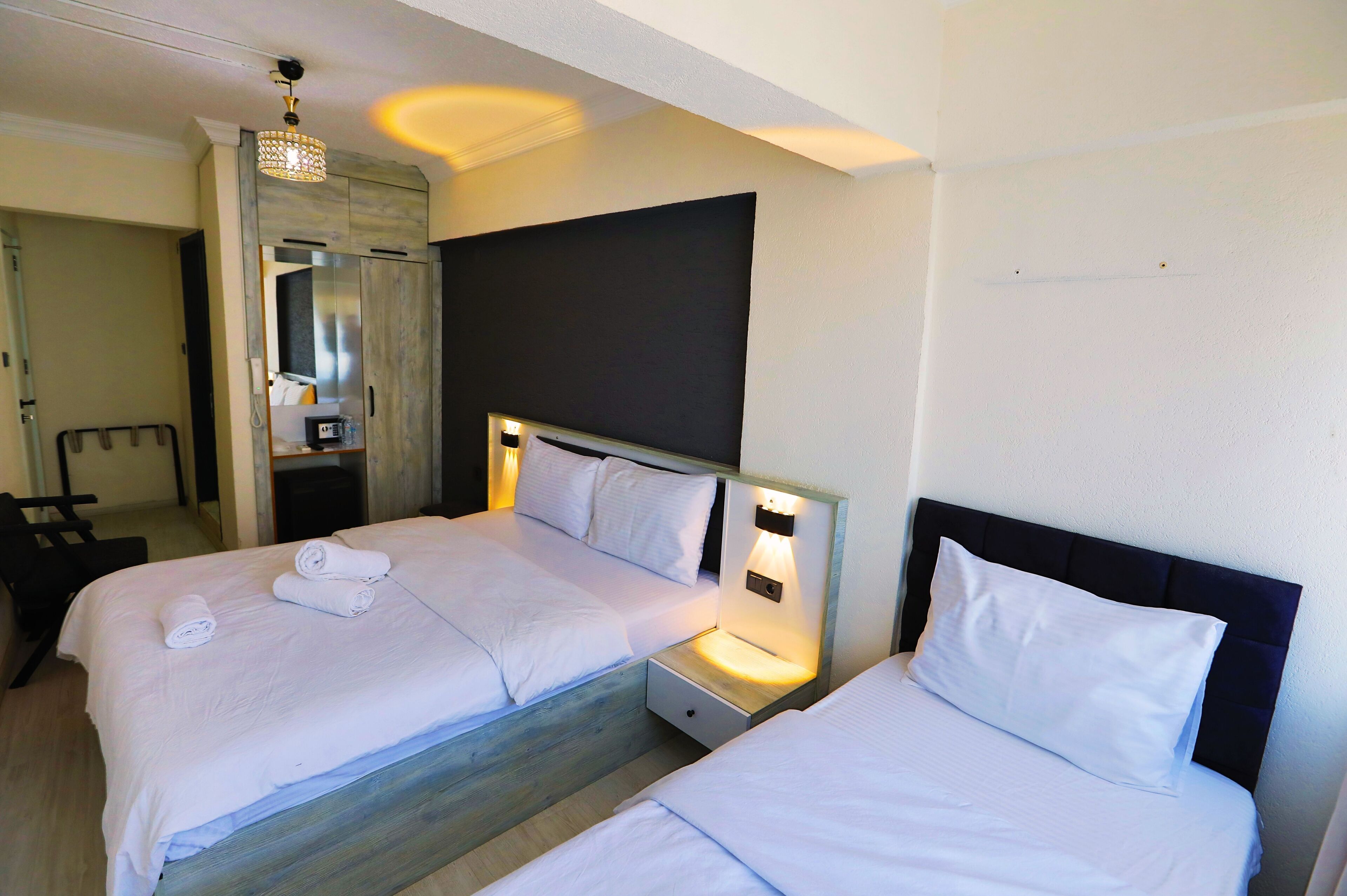 Ein Hotelzimmer mit zwei Betten, einem Nachttisch, einem Spiegel und einer Pendelleuchte.