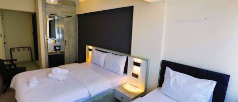 Ein Hotelzimmer mit zwei Betten, einem Nachttisch, einem Spiegel und einer Pendelleuchte.