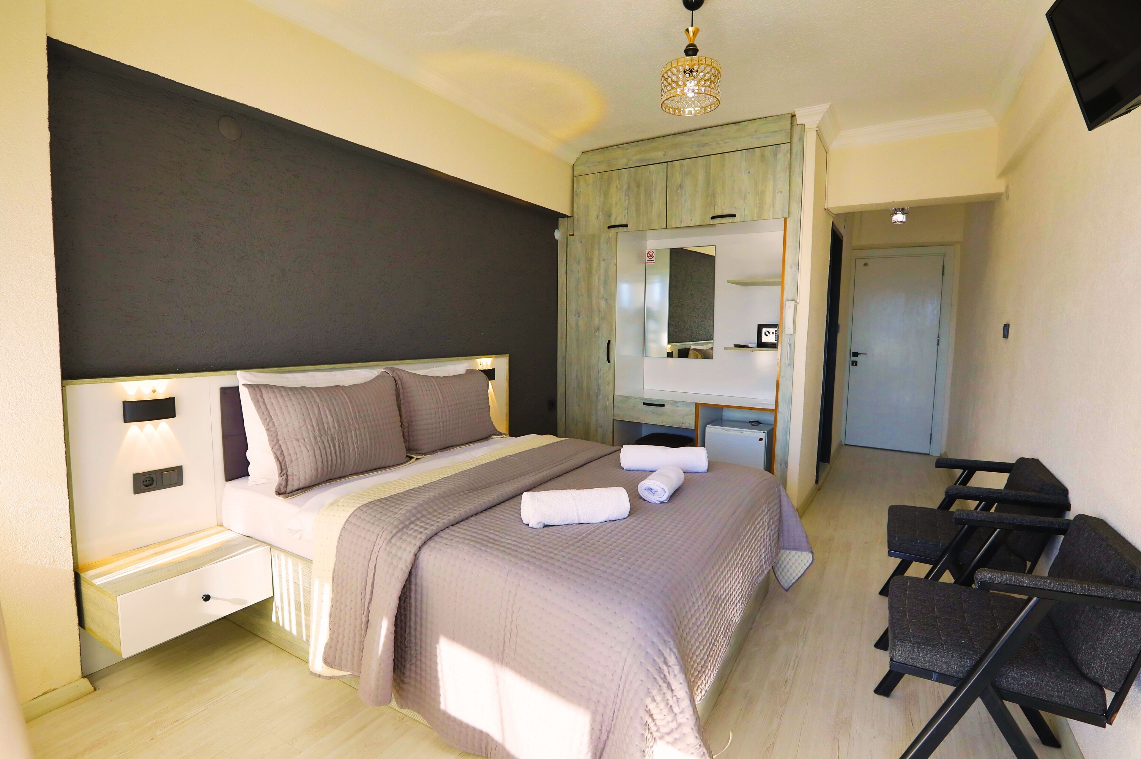Ein Schlafzimmer mit einem großen Bett, Nachttischen, einem Kleiderschrank, einem Schreibtisch und einem Sessel.