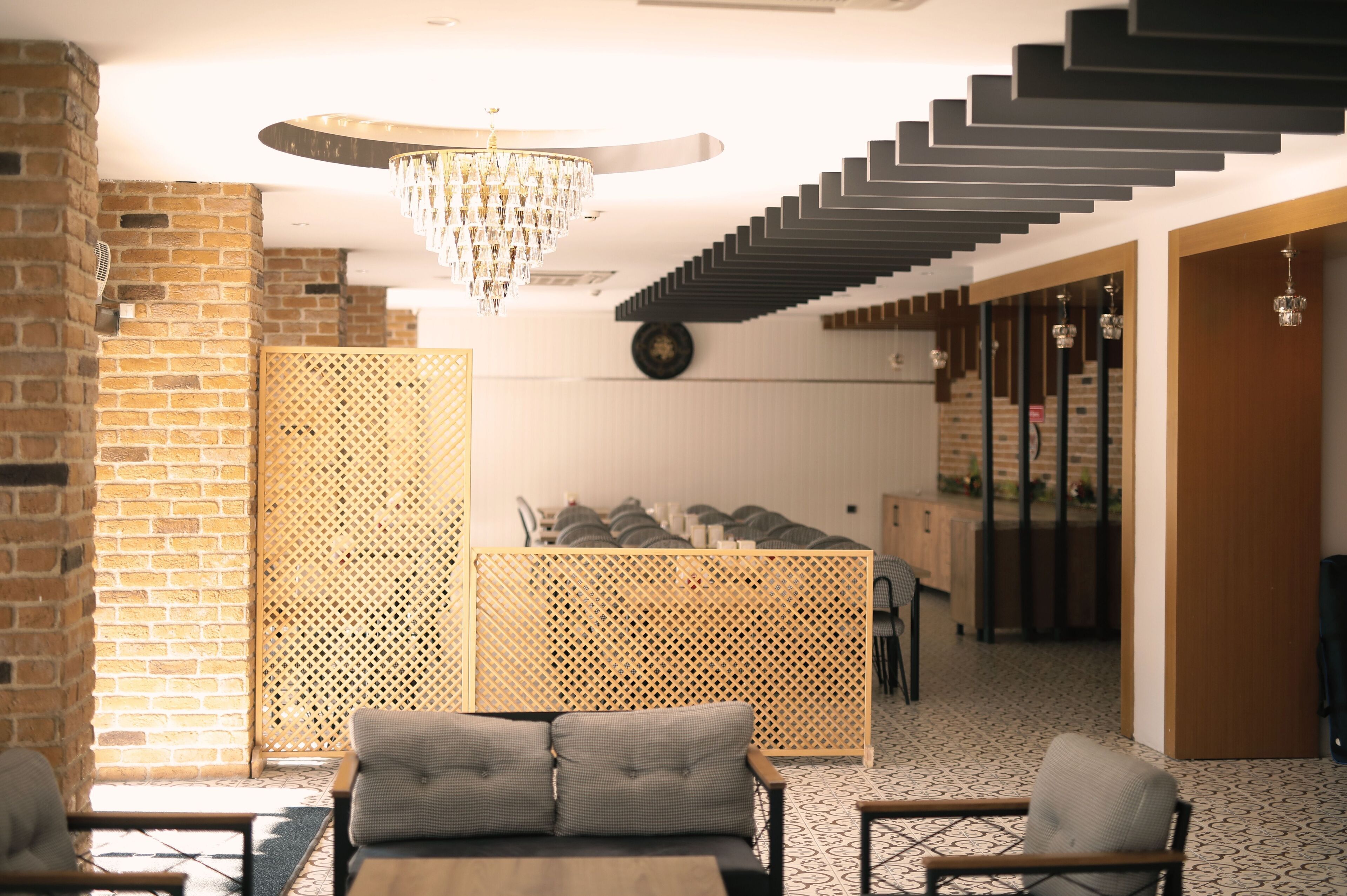 A modern interior with a staircase, a chandelier, and a seating area with a patterned rug.