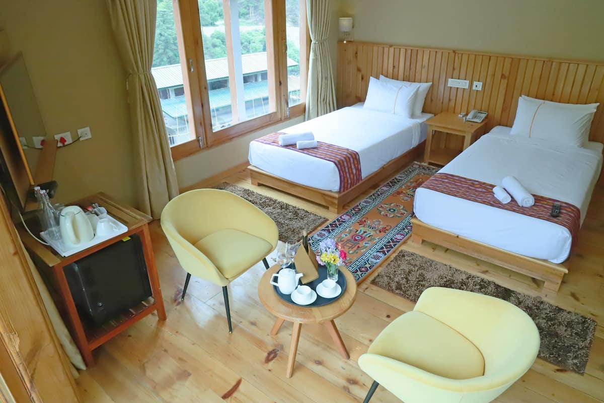 A hotel room with two beds, a TV, and two chairs.
