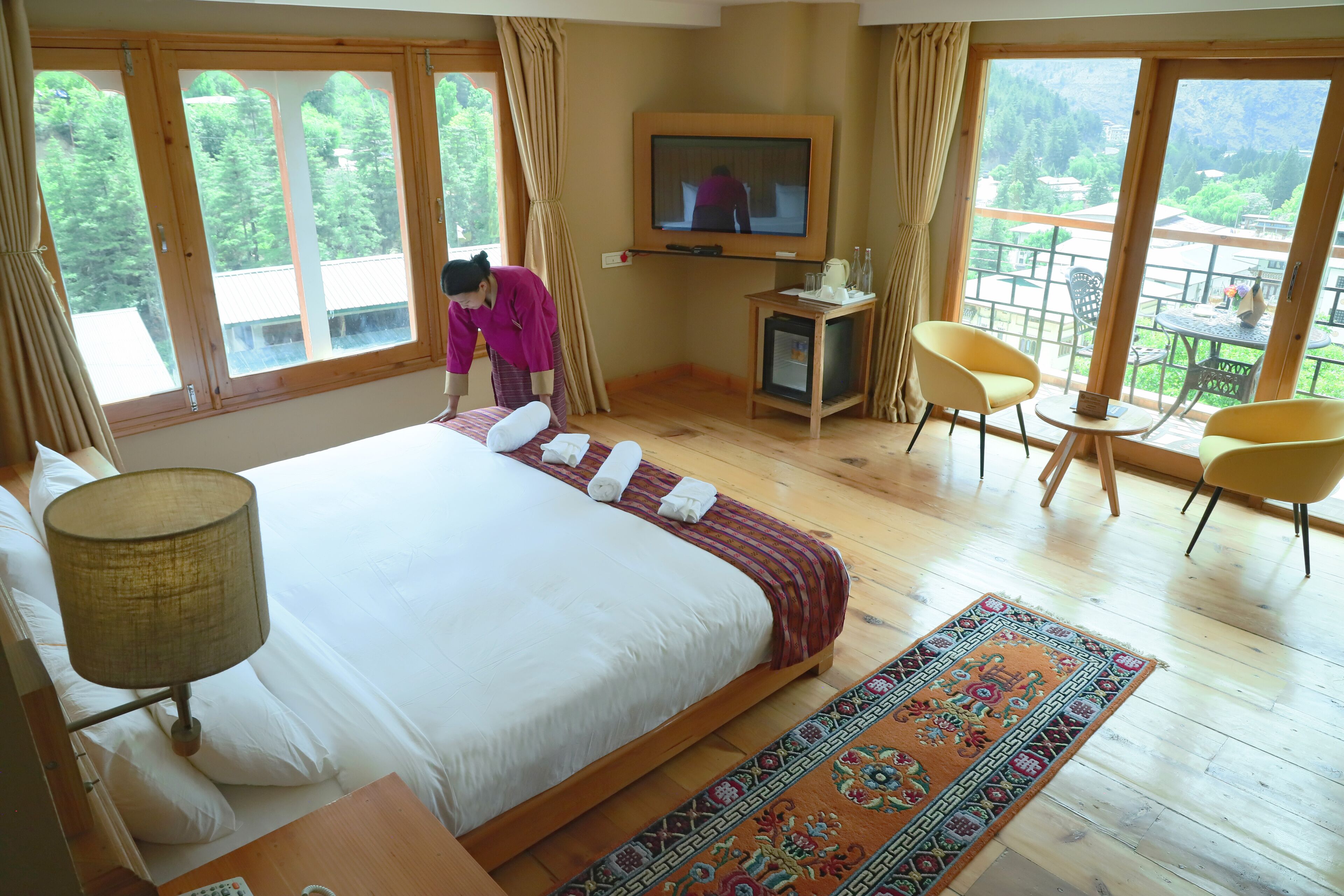 A hotel room with a large bed, a television, a small table, and two chairs.