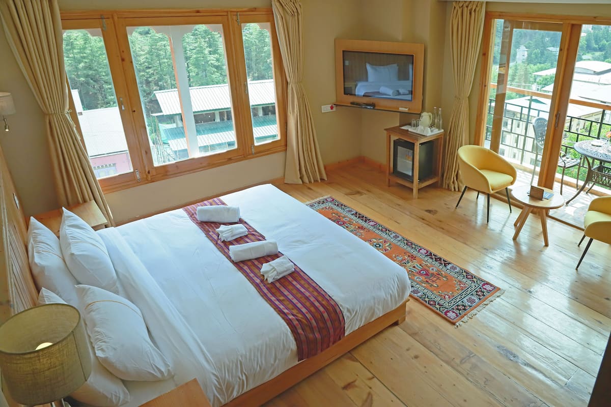 A bedroom with a large bed, a television, a small table, and a chair.