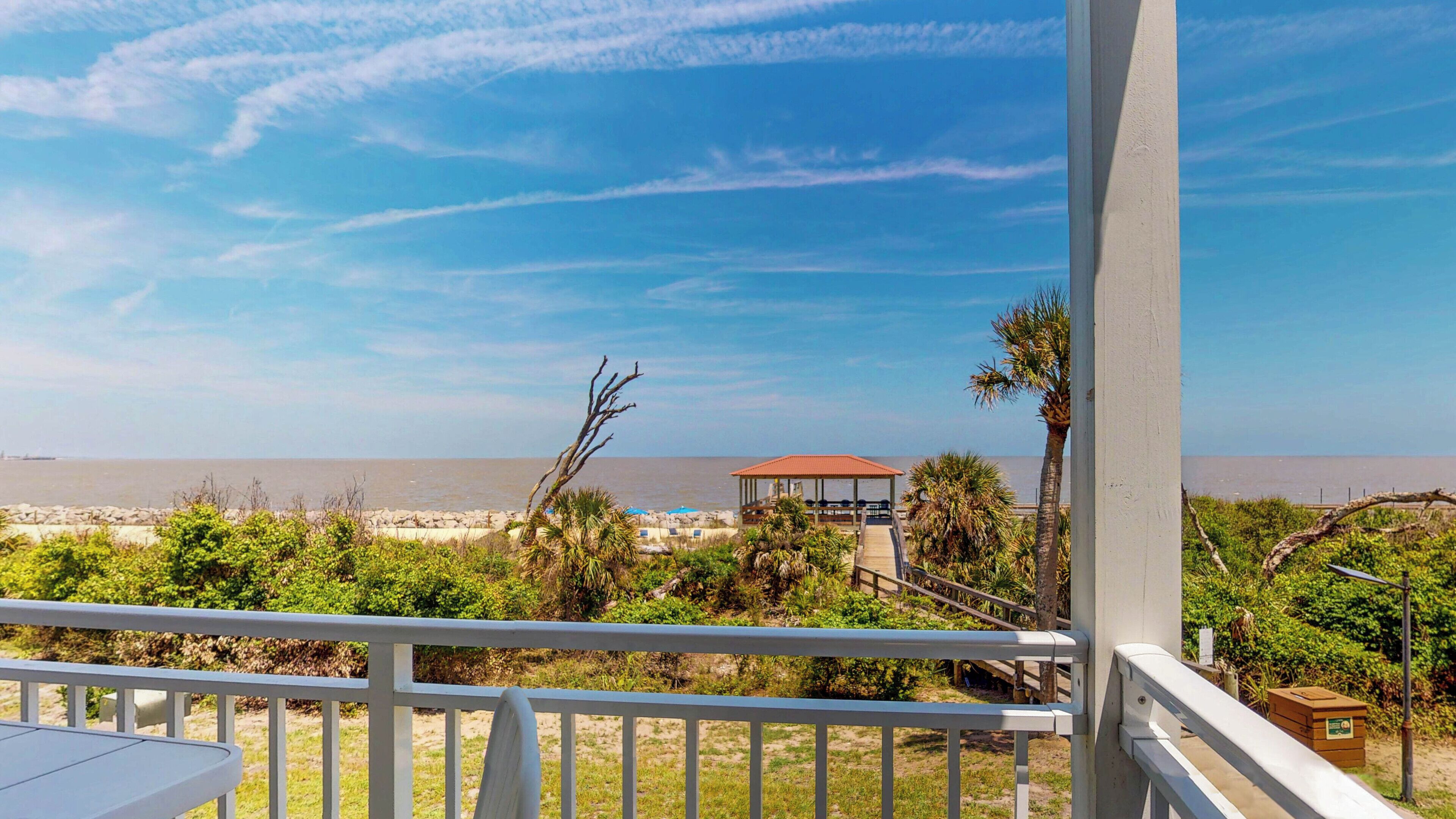 Un balcon avec vue sur la plage, un belvédère et quelques plantes.