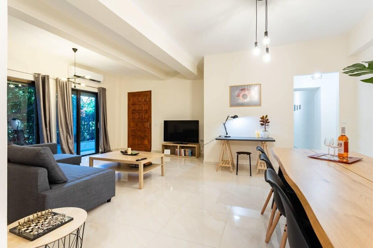 A modern living room with a sofa, coffee table, and a dining area with a long table and chairs.