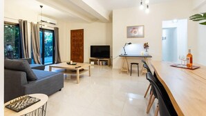 Ein modernes Wohnzimmer mit Sofa, Couchtisch und Essbereich mit langem Tisch und Stühlen.