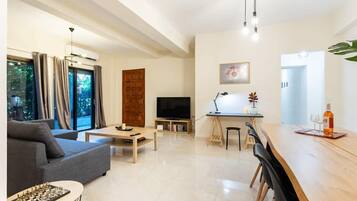 A modern living room with a sofa, coffee table, and a dining area with a long table and chairs.
