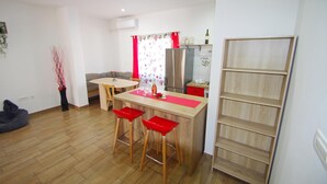 A modern kitchen with a central island, red bar stools, a dining table, and a built-in wooden shelf unit. - 2 bedroom holiday apartment in village Loborika, close to Pula (Loborika)