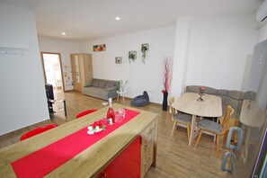 A modern living room with a wooden dining table, red runner, and a sofa.