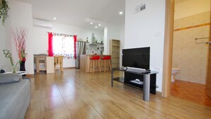 A modern living room with a sofa, a TV, and a kitchen area in the background. - 2 bedroom holiday apartment in village Loborika, close to Pula (Loborika)