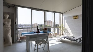 Ein modernes Zimmer mit einem großen Fenster, einer Statue, einem Tisch mit einer Flasche und Obst, und einem Schild mit der Aufschrift 'MUSIC ZONE'.