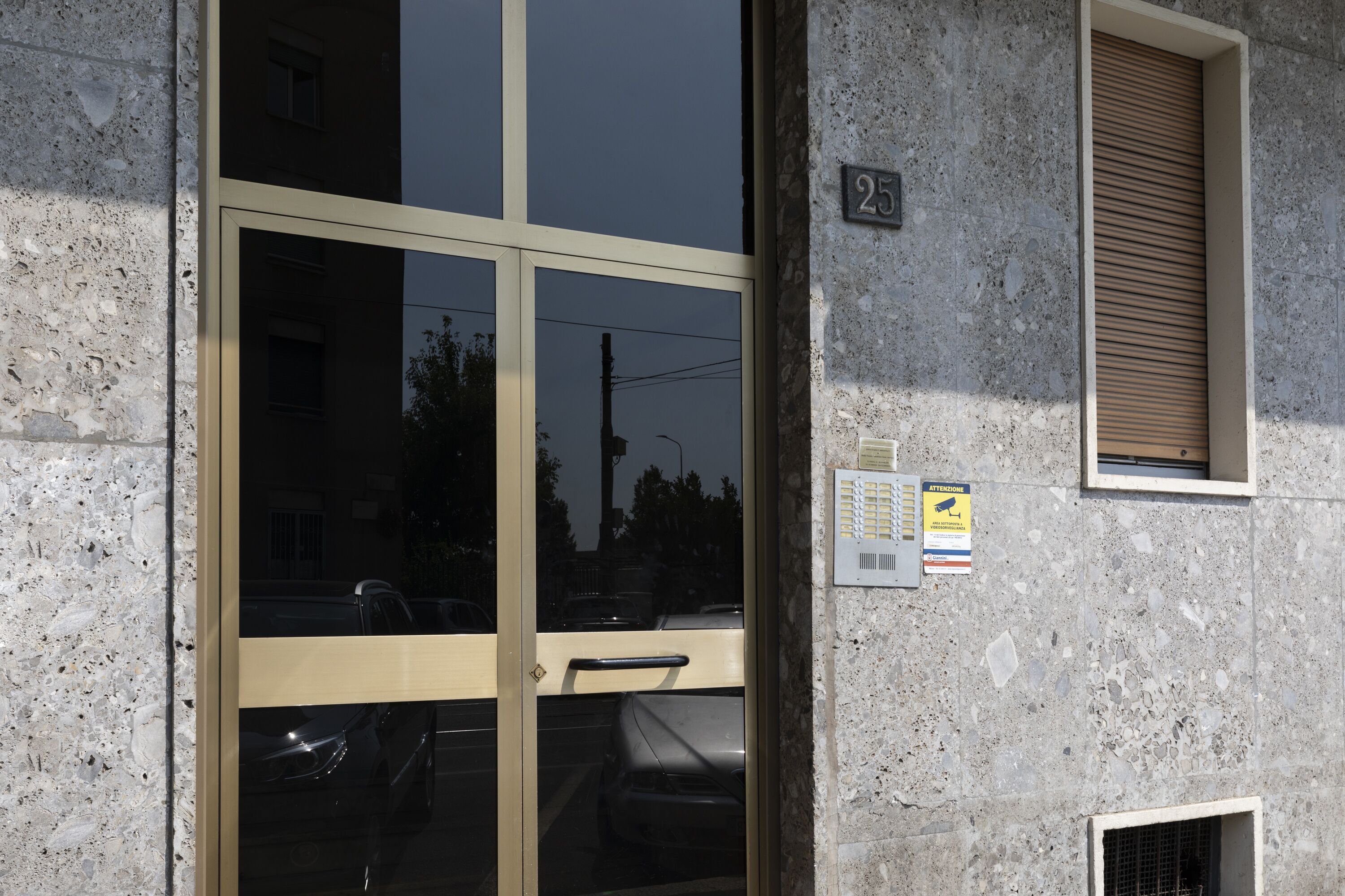 A building entrance with a glass door, a number '25' sign, and a ventilation unit.