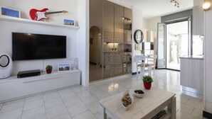 Ein modernes Wohnzimmer mit einem Flachbildfernseher, einer roten E-Gitarre und einem Essbereich mit Tisch und Stühlen.