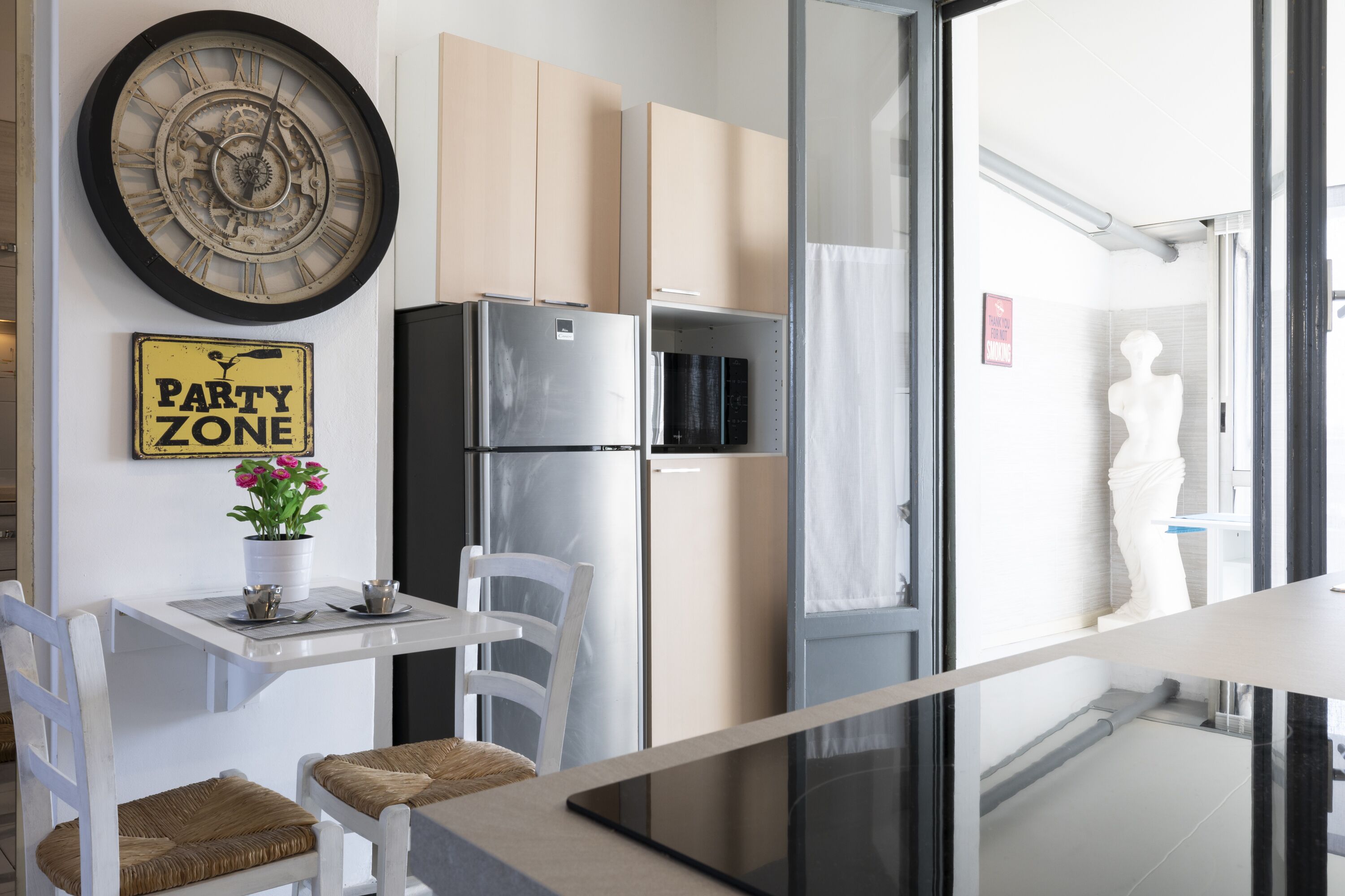 A modern kitchen with a refrigerator, a clock, and a 'Party Zone' sign.