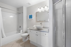 A modern bathroom with a bathtub, toilet, and a sink with a large mirror above it.