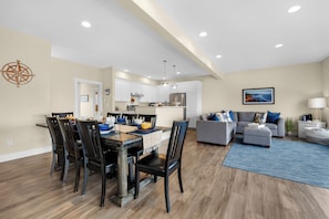 A spacious living area with a dining table, chairs, a sofa, and a kitchen in the background. - SUNSET DREAMS at Seaside Beach (Seaside)