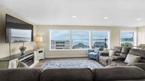 A living room with a large window, a flat-screen TV, and a sofa. - SUNSET DREAMS at Seaside Beach (Seaside)