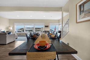 A spacious dining area with a long table, multiple chairs, and a view of the outside. - SUNSET DREAMS at Seaside Beach (Seaside)