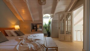 Ein Schlafzimmer mit einem großen Bett, einem Nachttisch, einer Bank und Blick auf einen Balkon.