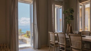 Ein Essbereich mit Tisch und Stühlen, Meerblick und ein Balkon mit Vorhängen.