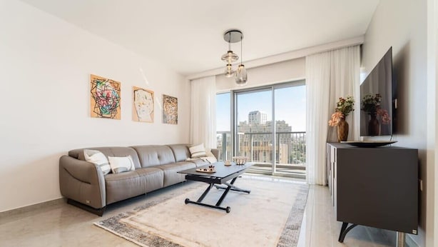 A modern living room with a sofa, coffee table, and artwork on the wall. - Enchanting 2 Bedroom In Best Location/Parking (Jerusalem)