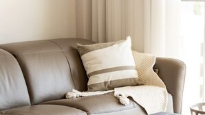A modern living room with a leather sofa, a coffee table with a plate of berries, and a cup of coffee. - Enchanting 2 Bedroom In Best Location/Parking (Jerusalem)