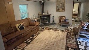 Ein gemütliches Wohnzimmer mit Kamin, Deckenventilator und einem gemusterten Teppich.