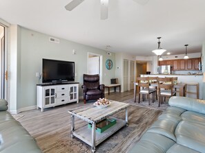 A living room with a television, leather chairs, a coffee table, and a sofa.