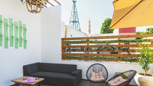 A patio with a sofa, chairs, a table, a potted plant, and a wooden fence with greenery. - Anemoessa Mansion in Rhodes Old Town (rhodes)