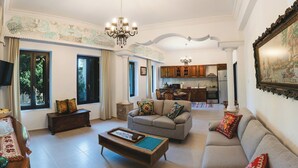 A living room with a sofa, coffee table, and a TV. There is a kitchen in the background. - Anemoessa Mansion in Rhodes Old Town (rhodes)