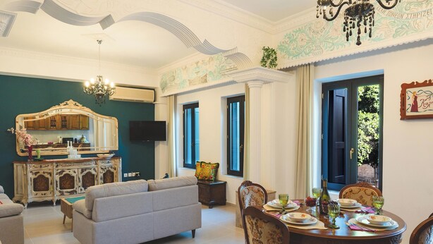 A dining area with a round table set for four, a sofa, and a television. - Anemoessa Mansion in Rhodes Old Town (rhodes)