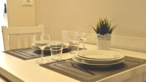 Una mesa de comedor dispuesta con platos, vasos y cubiertos, una pequeña planta en maceta y una silla.