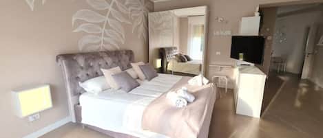 A bedroom with a large bed, a bedside table, a TV, and a mirror.