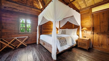 A wooden cabin bedroom with a four-poster bed, a nightstand, and a window with a view of greenery.
