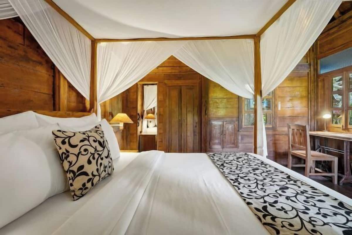Un dormitorio con cama a dosel, paredes de madera, un escritorio y una silla.