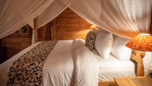Une chambre à coucher accueillante, avec un lit à baldaquin, une couvre-lit à motifs et une lampe de chevet.