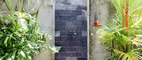 A stone wall with a water feature, surrounded by lush greenery.