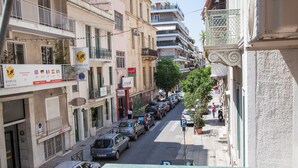 Vista da rua com carros estacionados, edifícios e um pedestre.