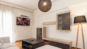 Uma sala de estar moderna com uma TV de tela plana, um sofá, uma mesa de centro, um rack para TV e um abajur.