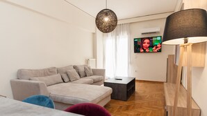 Uma sala de estar moderna com um sofá, uma mesa de centro e uma televisão fixada na parede.